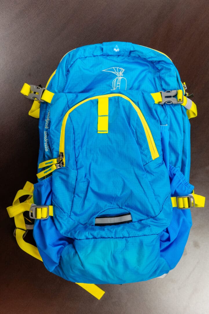 A blue backpack with yellow straps and buckles.